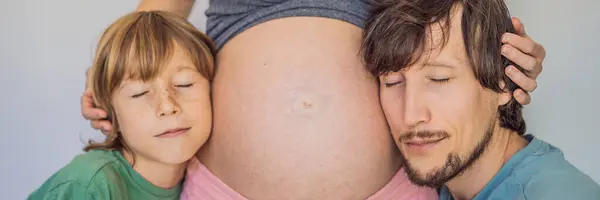 Father and elder son listen to moms pregnant belly. BANNER, LONG FORMAT