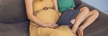 pregnant mom and son look at the tablet. Reading a book or watching a cartoon or making a video call. Look at the photo from the ultrasound. BANNER, LONG FORMAT clipart