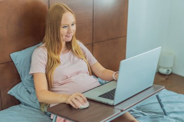 Bilgisayarda çalışan hamile bir kadın. Beklenen kadın hamilelik sırasında evden verimli bir şekilde çalışıyor, mesleki bağlılığı annelik görevleriyle harmanlıyor..