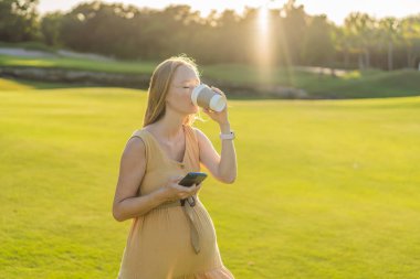 Hamile bir kadın, doğanın basit zevkleriyle hamileliği boyunca içeceği rahatlatıcı sıcaklığı harmanlayarak dışarıda kahve içmeyi sever..
