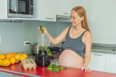 Besleyici bir seçimi kucaklayan hamile bir kadın neşeli bir şekilde canlı bir sebze kokteyli hazırlar ve hamilelik yolculuğunda en iyi koşullarda yaşayabilmesi için sağlıklı malzemelere öncelik verir..