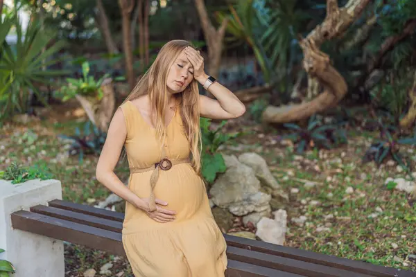 妊娠中の女性は 妊娠中に頭痛を伴う不快な瞬間を経験し 共通の課題と適切なセルフケアと母親の井戸への注意の必要性を強調しています — ストック写真