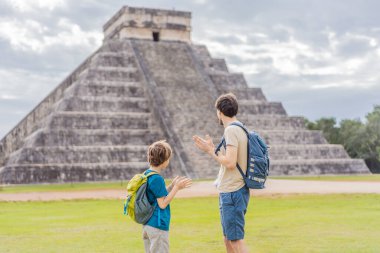 Baba ve oğul turistler Chichen Itza olarak bilinen Maya mimarisinin eski piramit ve tapınağını izliyorlar. Bunlar eski Kolombiya öncesi medeniyetin kalıntıları.