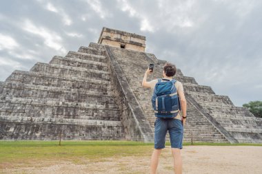 tourist man observing the old pyramid and temple of the castle of the Mayan architecture known as Chichen Itza. These are the ruins of this ancient pre-columbian civilization and part of humanity. clipart