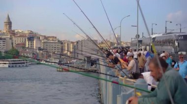5.05.2021 - ISTANBUL, TURKEY: Balıkçılar, Istanbullar 'ın akan suları ve şehir yaşamının bir zeminine karşı avlarını ararken, ellerinde direklerle hareketli Galata Köprüsü' nde kuyruk oluşturuyorlar.