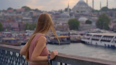 Genç bir kadın turistin tarihle modern hayatın kesiştiği İstanbul 'daki Galata Köprüsü' nden ikonik manzaranın tadını çıkardığı canlı bir manzara gözler önüne seriliyor.