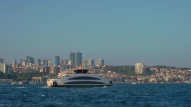 Büyük bir feribot İstanbul Boğazı 'ndan geçerek kalabalık şehir manzarasının Avrupa ve Asya taraflarını birbirine bağlar. Yavaş çekim videosu