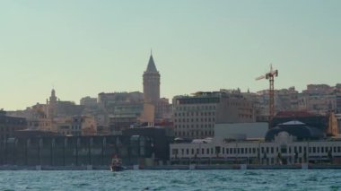 Tekneyle sakin bir yavaş çekim yolculuğu İstanbullar 'ın ikonik Galata Kulesi' nin çarpıcı bir görüntüsünü sunuyor. Şehrin ufuk çizgisinin üzerinde görkemli bir şekilde yükseliyor.