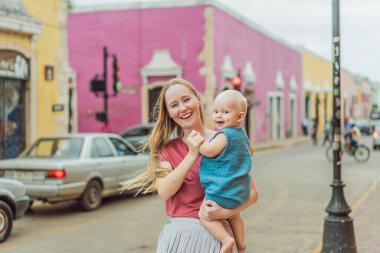 Mother and baby son tourists explore the vibrant streets of Valladolid, Mexico, immersing herself in the rich culture and colorful architecture of this charming colonial town. clipart