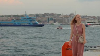 Galataport 'un canlı atmosferine dalan genç bir kadın turist, iskele boyunca neşeli bir yürüyüşle İstanbul' un cazibesine kapılıyor.