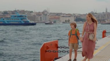 Galataport 'un canlı atmosferine dalan genç bir kadın ve oğlu turistler, iskele boyunca neşeli bir yürüyüşle İstanbul' un cazibesine kapıldılar.