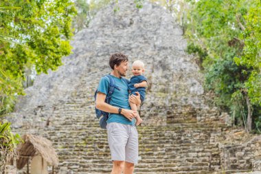Baba ve oğul turistler Coba, Meksika 'da. Meksika 'daki antik Maya şehri. Coba arkeolojik bir alan ve Yucatan Yarımadası 'nın ünlü bir simgesidir. Meksika 'da bir piramidin üzerindeki bulutlu gökyüzü.