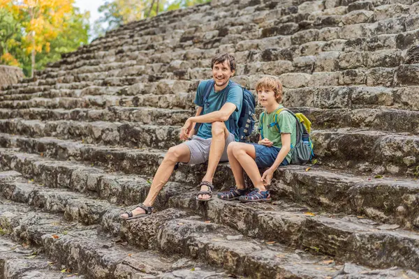 Baba ve oğul turistler Coba, Meksika 'da. Meksika 'daki antik Maya şehri. Coba arkeolojik bir alan ve Yucatan Yarımadası 'nın ünlü bir simgesidir. Meksika 'da bir piramidin üzerindeki bulutlu gökyüzü.