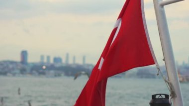 Türk bayrağı dalgalanırken, yakınlarda dalgalanan martılarla birlikte, İstanbulların canlı arkaplanına vuruyor..