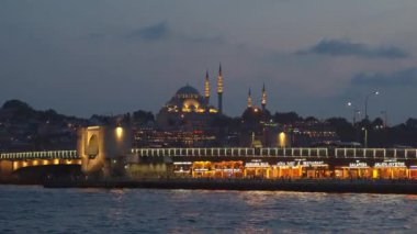 5.08.2022, ISTANBUL, TURKEY: Istanbuls tarihi merkezi gece canlanır güzel aydınlatılmış bir cami ve Golden Horn körfezi boyunca uzanan Galata Köprüsü 'nün parıldayan ışıkları ile