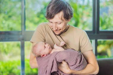 Babam ve yeni doğmuş bebek evde. Bu hassas an, baba ve çocuk arasındaki sevgi dolu ve rahat aile ortamını yakalar. Ebeveynliğin neşesini ve evin sıcaklığını vurgular..