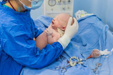 Hastane ortamında yeni doğmuş bir bebeğe bakan bir hemşire. Hemşire, bebeğin rahatı ve refahını sağlamak için nazik ve özenli bir bakım sağlar..
