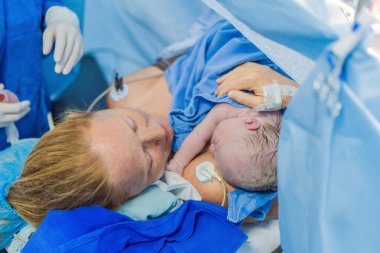 Hastanede doğduktan hemen sonra anne göğsünde bir bebek. Anne ve yeni doğan, duygusal bağ ve bağın vurgulandığı hassas bir anı paylaşıyor. Sağlık personeli güvenli ve şefkatli olmasını sağlıyor.