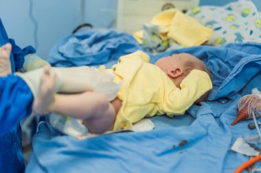 Hastane ortamında yeni doğmuş bir bebeğe bakan bir hemşire. Hemşire, bebeğin rahatı ve refahını sağlamak için nazik ve özenli bir bakım sağlar..