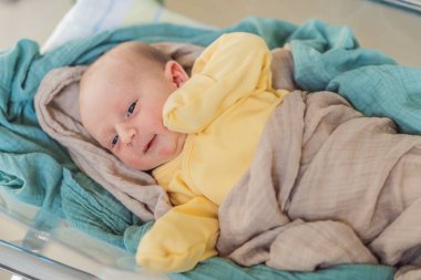 A newborn rests peacefully in his transparent bassinet in the hospital. The clear bassinet provides visibility for medical staff to monitor the babys well-being while ensuring a safe and comfortable clipart