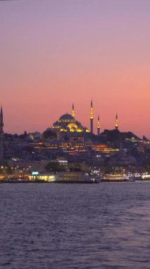 Günbatımında, bir feribot İstanbul 'un tarihi kent merkezine huzurlu bir bakış açısı sunuyor, solan güneş ışığı eski yapıları sıcak bir ışıltıyla yıkıyor.