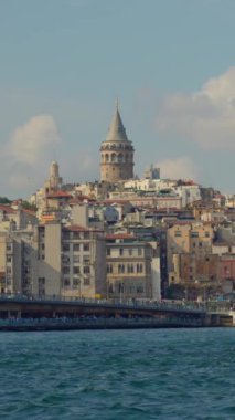 Tekneyle yapılan sakin bir yavaş çekim yolculuğu İstanbullar 'ın ikonik Galata Kulesi' nin çarpıcı bir görüntüsünü sunuyor. Şehir siluetinin üzerinde görkemli bir şekilde yükseliyor. Dikey video