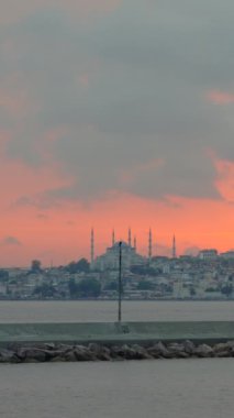 Hareketli bir tekneden İstanbul 'un görkemli bir günbatımı, Aya Sophia, Mavi Cami ve Topkapı Sarayı' nı kızgın gökyüzüne vurguluyor. Yavaş çekim videosu. Dikey biçim