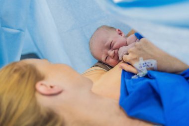 Hastanede doğduktan hemen sonra anne göğsünde bir bebek. Anne ve yeni doğan, duygusal bağ ve bağın vurgulandığı hassas bir anı paylaşıyor. Sağlık personeli güvenli ve şefkatli olmasını sağlıyor.