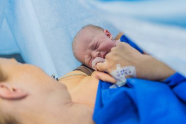 Hastanede doğduktan hemen sonra anne göğsünde bir bebek. Anne ve yeni doğan, duygusal bağ ve bağın vurgulandığı hassas bir anı paylaşıyor. Sağlık personeli güvenli ve şefkatli olmasını sağlıyor.