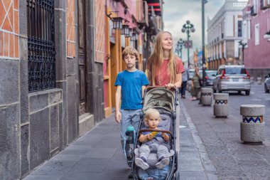 Meksika, Puebla 'nın renkli sömürge sokaklarında yürümekte olan küçük çocukları ve ergen çocuklarıyla birlikte anne turist. Seyahat, kültürel keşif ve canlı mimari konsepti..