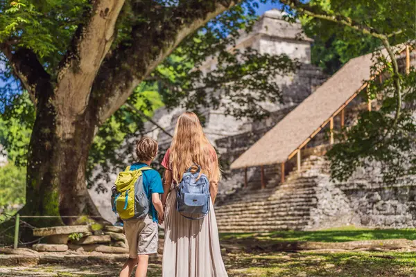 stock image Mother and son tourists exploring the ancient pyramids of Palenque, Mexico, surrounded by dense jungle. Cultural heritage and adventure travel concept.