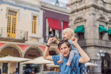 Küçük oğluyla birlikte Puebla, Meksika 'nın renkli sömürge sokaklarında yürüyen baba turist. Seyahat, kültürel keşif ve canlı mimari konsepti..