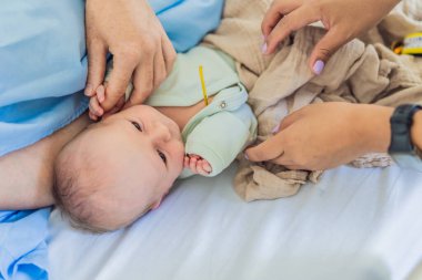 Hastanede bir hemşire bebek sıcaklığını ölçüyor. Nazik ve dikkatli bir işlem, bebeklerin rahatlığını ve iyiliğini sağlar ve sağlıklarının doğru bir şekilde izlenmesini sağlar..