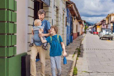 Baba ve iki oğlu, bir genç ve bir bebek turist San Cristobal de las Casas, Meksika 'da koloni sokaklarında yürüyorlar. Kültürel keşif, mimari ve seyahat deneyimi konsepti.