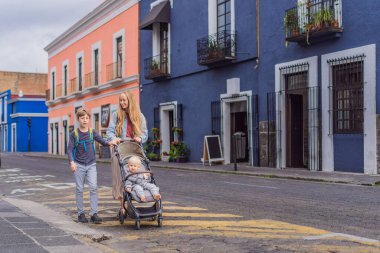 Meksika, Puebla 'nın renkli sömürge sokaklarında yürümekte olan küçük çocukları ve ergen çocuklarıyla birlikte anne turist. Seyahat, kültürel keşif ve canlı mimari konsepti..