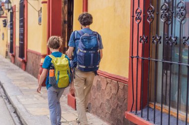 Baba ve iki oğlu, bir genç ve bir bebek turist San Cristobal de las Casas, Meksika 'da koloni sokaklarında yürüyorlar. Kültürel keşif, mimari ve seyahat deneyimi konsepti.