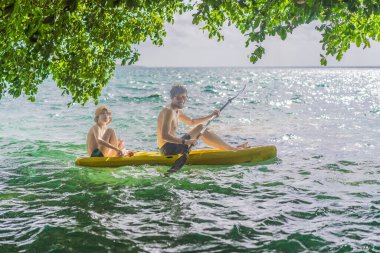 Baba ve oğul turistler Meksika 'daki Bacalar Gölü' nde kayak yapıyorlar. Quintana Roo 'da macera turizmi, açık hava keşfi ve su aktiviteleri konsepti.