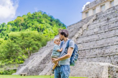 Mother with his toddler son exploring the ancient pyramids of Palenque, Mexico, surrounded by dense jungle. Cultural heritage and adventure travel concept. clipart