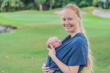 Annem yeni doğmuş bebeğiyle askıda yürüyor. Bu an, anne ve çocuk arasındaki yakın bağın altını çiziyor. Günlük hayatta rahatlığı, güvenliği ve bebek giyiminin faydalarını destekliyor..