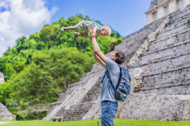 Mother with his toddler son exploring the ancient pyramids of Palenque, Mexico, surrounded by dense jungle. Cultural heritage and adventure travel concept. clipart