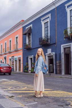 Female tourist walking through the colorful colonial streets of Puebla, Mexico. Travel, cultural exploration, and vibrant architecture concept. clipart