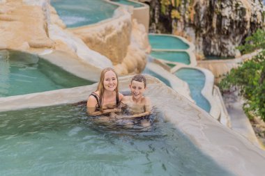 Mother with her toddler and teenage sons bathing in the hot springs of Grutas Tolantongo, Mexico. Family adventure, relaxation, and natural wellness concept. clipart