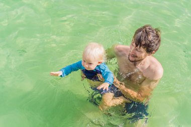 Baba ve küçük oğlu Bacalar Gölü 'nün turkuaz sularında yüzüyorlar. Aile bağı, yaz tatili ve Quintana Roo 'da açık hava eğlencesi, Meksika konsepti..