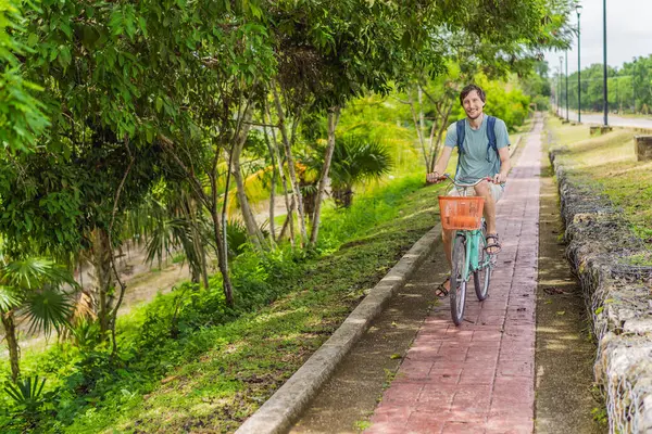 Meksika 'nın büyüleyici Bacalar köyünde bisiklet süren bir adam. Quintana Roo seyahati, manzaralı bisiklet yolları ve çevre dostu keşif konsepti..