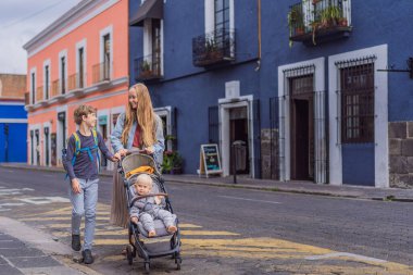 Meksika, Puebla 'nın renkli sömürge sokaklarında yürümekte olan küçük çocukları ve ergen çocuklarıyla birlikte anne turist. Seyahat, kültürel keşif ve canlı mimari konsepti..
