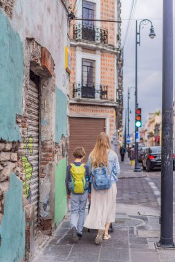 Meksika, Puebla 'nın renkli sömürge sokaklarında yürümekte olan küçük çocukları ve ergen çocuklarıyla birlikte anne turist. Seyahat, kültürel keşif ve canlı mimari konsepti..