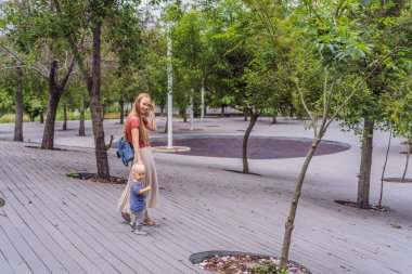 Anne ve küçük oğlu parkta yürüyorlar. Aile bağları, açık hava keşifleri ve ebeveynlik kavramı..