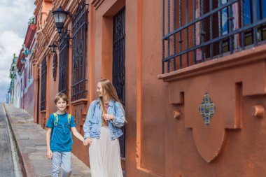 Annesi ve oğlu turistler San Cristobal de las Casas, Meksika 'da koloni sokaklarında yürüyorlar. Kültürel keşif, mimari ve seyahat deneyimi konsepti.