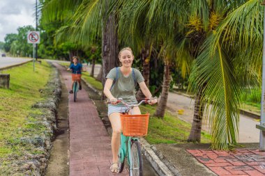 Kadın turist ve oğlu Meksika 'nın büyüleyici Bacalar köyünde bisiklet sürüyorlar. Quintana Roo seyahati, manzaralı bisiklet yolları ve çevre dostu keşif konsepti..