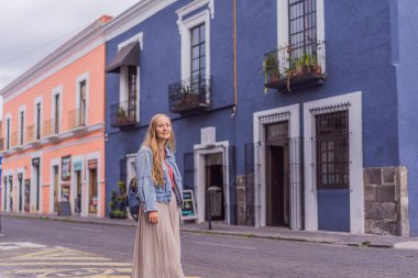 Puebla, Meksika 'nın renkli koloni sokaklarında yürüyen kadın turist. Seyahat, kültürel keşif ve canlı mimari konsepti..